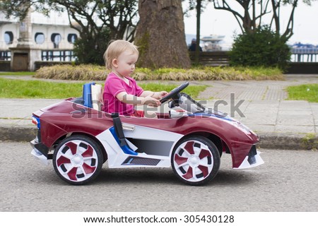Baby girl riding on a small car