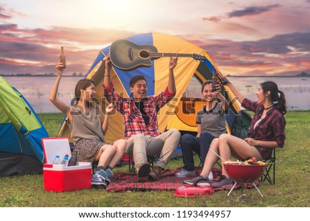 Travel Group of Asian Friends Enjoy Camping Tent Party , They are Enjoying Sing a Song with Guitar at Camp in Summer Evening - Travel and Recreation Concept