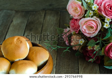 Still Life Style of Mini Bun Tuna Bread Recipe in Wooden Bowl and Fake Flowers Prop Setting on the Wooden Table - Texture Background