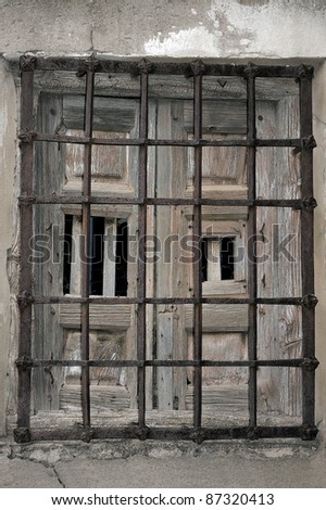 Old abandoned window with rusty iron bars.