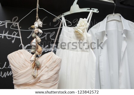Wedding dress and suit hanging at a wall