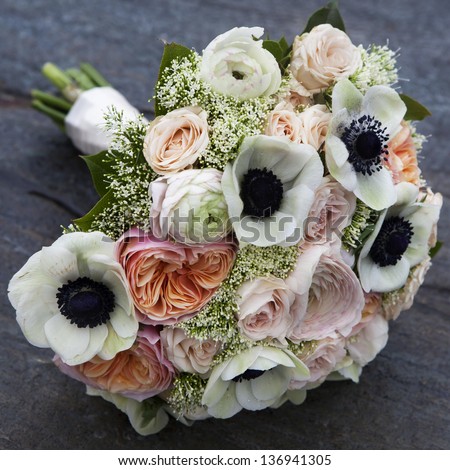 Wedding bouquet of pink roses and white anemone and pink ranunculus lying on wooden floor