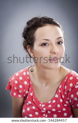 young caucasian female in red blouse isolated on grey background. Fresh natural makeup, big brown eyes, long lashes, gentle soft pink lipstick. Tied romantic hairstyle.