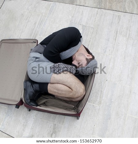 pensive man in check cap lying in broken trunk trying to escape