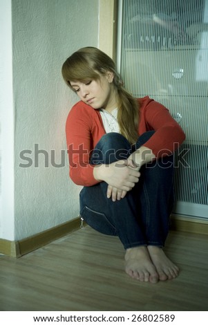 portrait of thoughtful young girl sitting on the corner of room. Teen`s problem