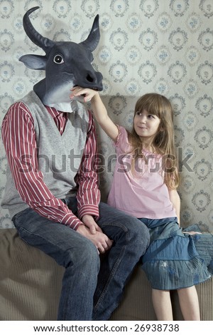 little girl playing with her older brother. Sister wearing diadem . Brother wearing mask of bull. Brother and sister sitting at the sofa