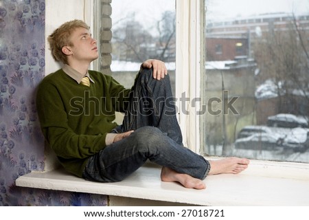 young handsome blond man sitting on the window-sill. Student problems. First love