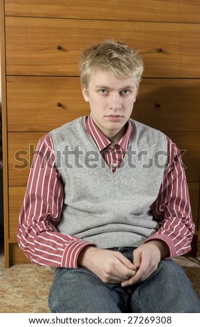 portrait of young handsome blond man sitting on the floor