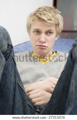 closeup portrait of young blond sad crying man with blue eyes. Teen`s problem