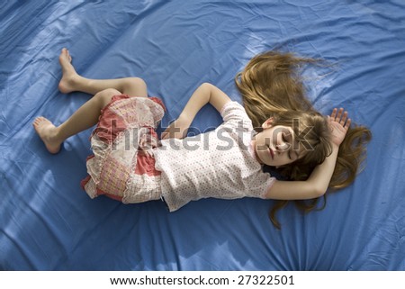 little sleeping girl lying on the bed. Blue cotton sheet