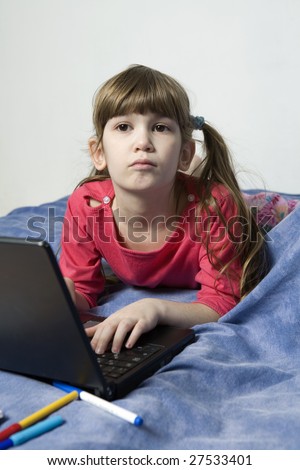 little cute pensive girl seven years old playing on laptop