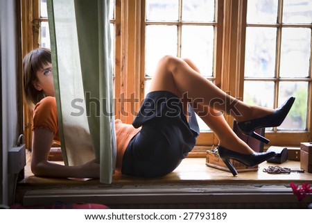 attractive woman wearing skirt in shoes with heels lying on window-sill