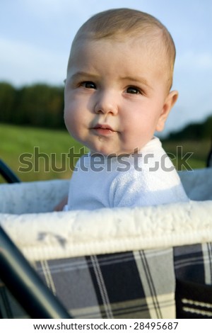 little cute boy six month old sitting on buggy
