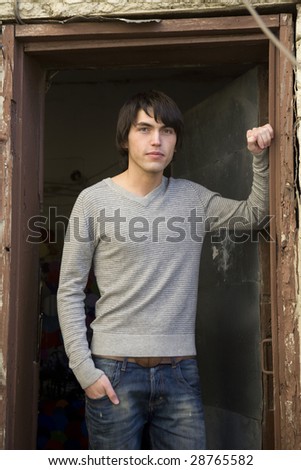 young attractive serious man standing at door stud