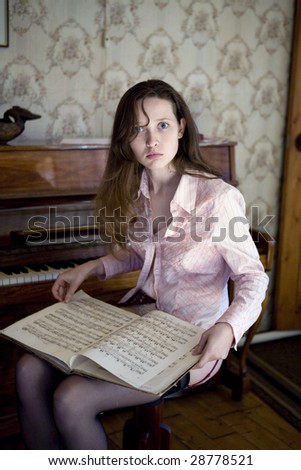 Young woman sitting on piano in empty room