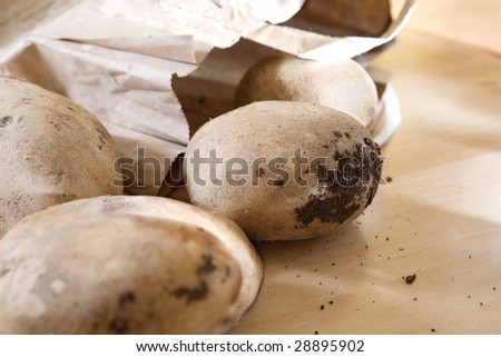 Dirty potato with earth in parcel  on the table. Organic food. microbe in earth. Sharpeness on earth