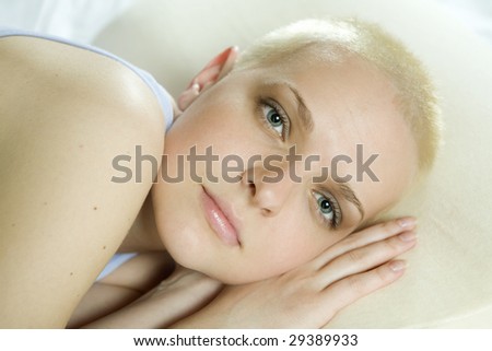 thoughtful blond bald woman lying on the bed