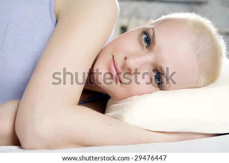 portrait of thoughtful blond bald woman lying on the bed