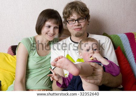 Young family. Blond father cuddle his son. Mother sitting at him