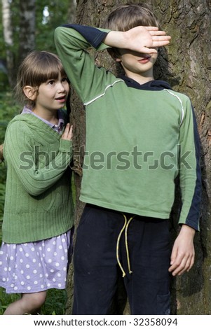 Girl and boy playing hide-and-seek. Boy close his eyes by hand