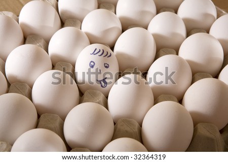 Chiken eggs in box. One egg cover with drawings. Look like man`s face