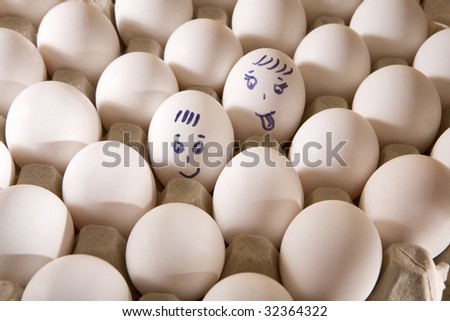 Hen`s eggs in box. One egg cover with drawings. Look like man`s face