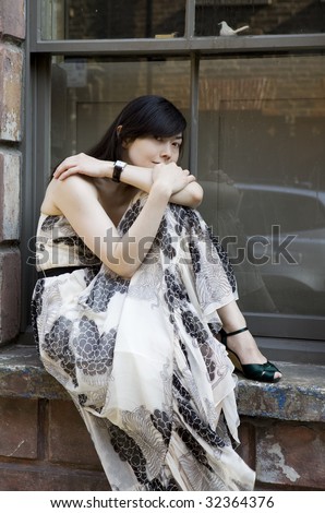 young attractive pensive woman in long dress sitting on stairs