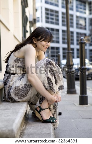 young attractive smiling woman in long dress sitting on stairs