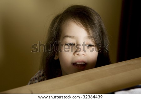 little cute girl looking behind bookshelf