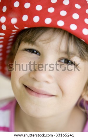 portrait of young smiling girl eight years old in big red panama in spotted