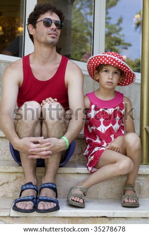 serious father with sad daughter sitting on stairs