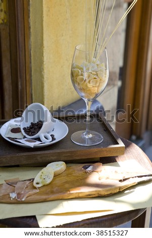 Coffee beans in a white cup and pasta in glasses. Table near caffe