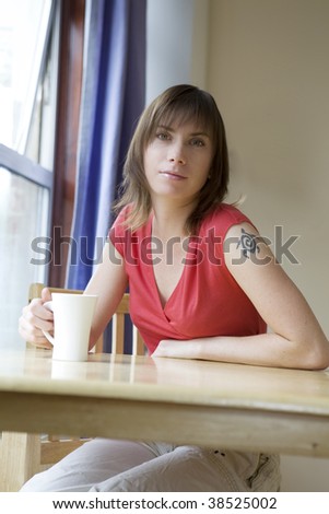 serious woman in red shirt sitting at table