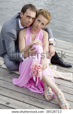 bride and groom sitting at river