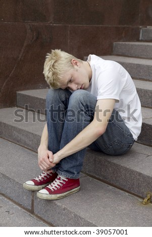 upset young man sitting on stairs put his head on knees