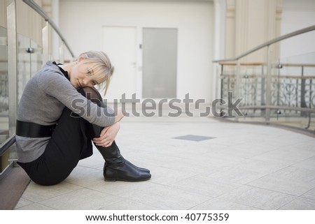 sad woman sitting on floor at big store resting after shopping