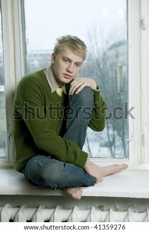 young handsome man sitting on the window-sill