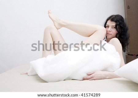 curl brunette serious woman lying on bed cover blanket