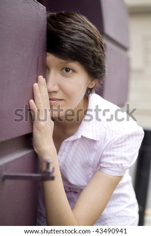 serious woman looks out from behind the wall