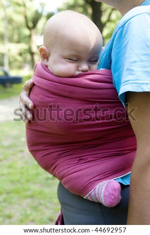little cute girl sleeping in sling. Mother`s hand hold her. Summer time