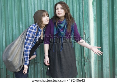 two smoking girls standing at the fence