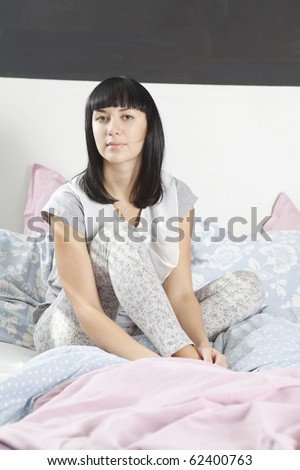 young serious woman wake up early morning and sitting on bed