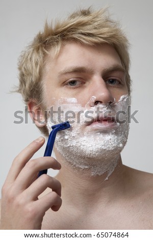 Blonde man shaving face in bathroom, portrait