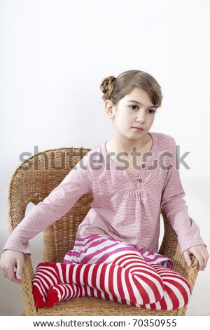 Calm little girl sitting on chair and looking ahead