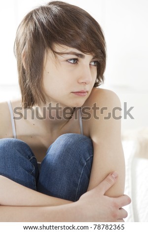 sad girl sitting on the bed hugging her knees
