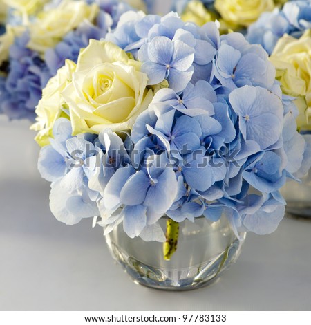 Bouquet of white and blue flower in vase of glass. Decoration of dining table.