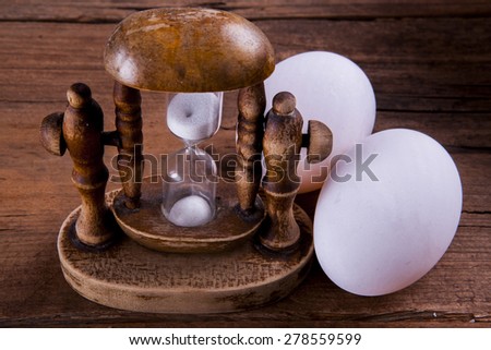 old fashion egg timer with two eggs shot at an angle on a wooden background