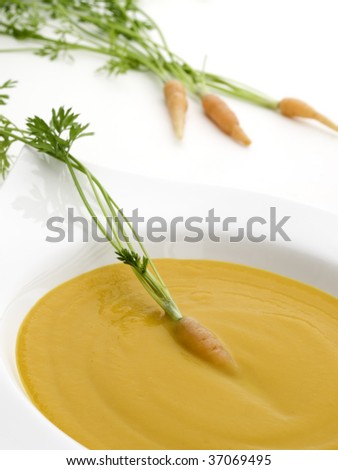 carrot cream on white served on a white bowl with a carrot vegetable on it