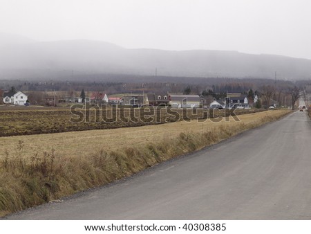 rural scene with building and mountain in the background. Fog and cloudy bad weather.