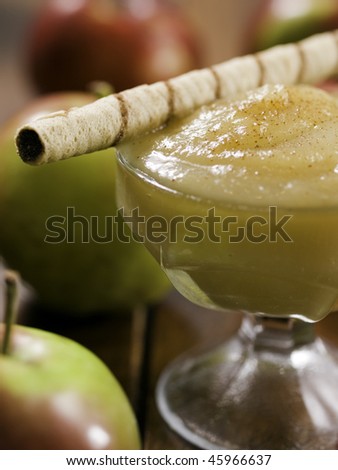 apple sauce dessert (stewed apple) on a wooden table with whole apples around. Shallow depth of field.
